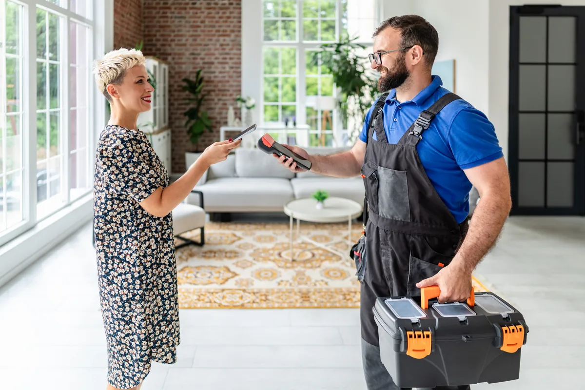 Homeowner shaking hands with a visiting technician carrying a toolbox