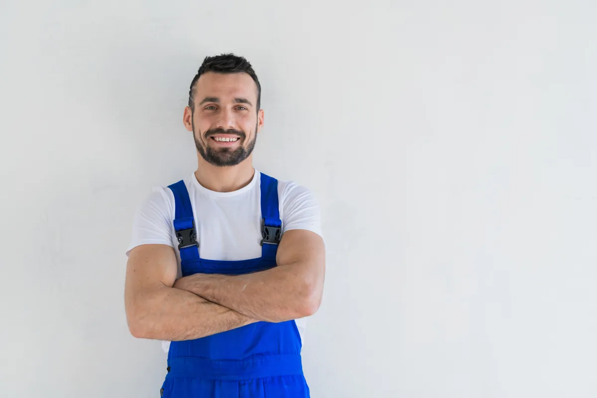 Service technician in blue overalls with arms folded