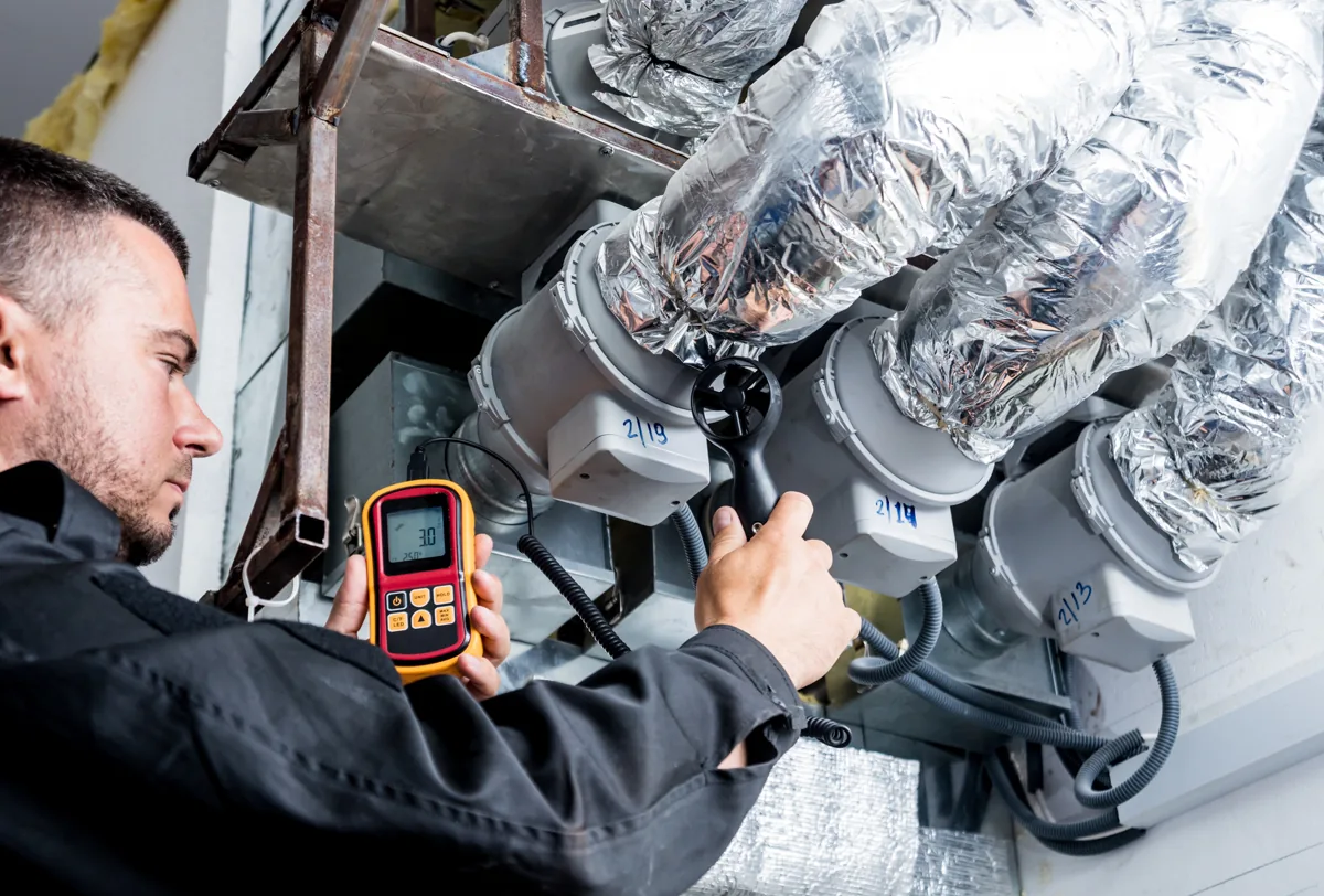 Technician checking airflow beside insulated ductwork